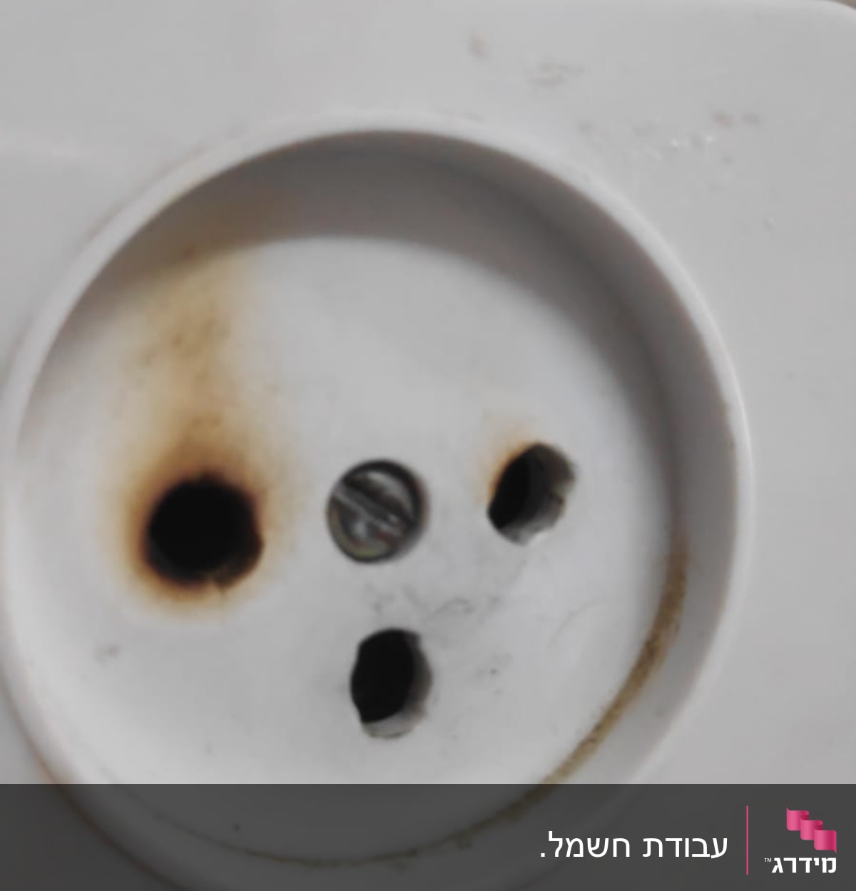 שקע חשמלי עם סימני שריפה סביב החורים